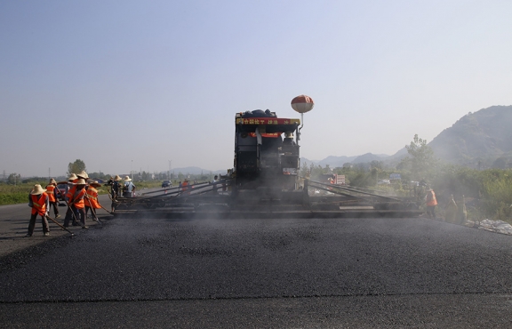 2019年8月，宜春經(jīng)開區(qū)S311路面攤鋪現(xiàn)場(chǎng)，工友們輔助路面兩側(cè)的分料、補(bǔ)窩等作業(yè)
